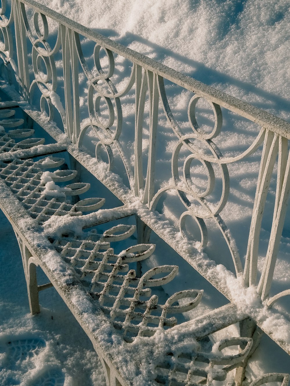 a white metal bench covered in snow