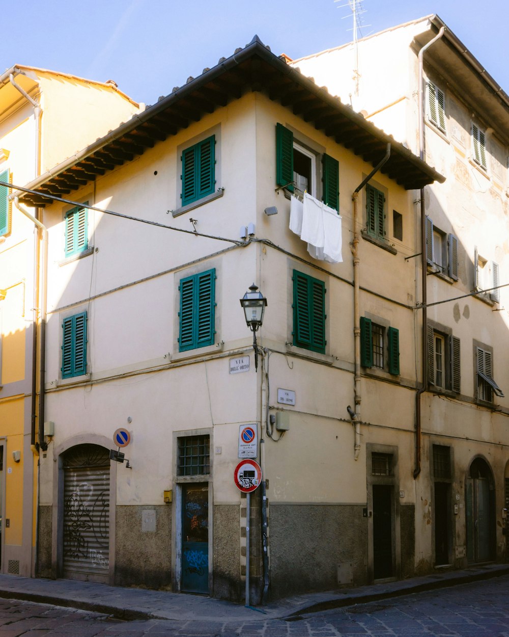 a building with green shutters and a street sign