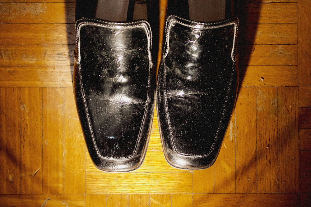 a pair of black shoes sitting on top of a wooden floor