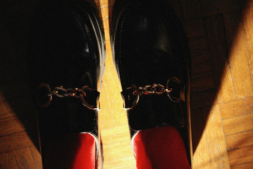 a pair of black and red shoes on a wooden floor