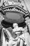 a statue of a man holding a book in front of a building