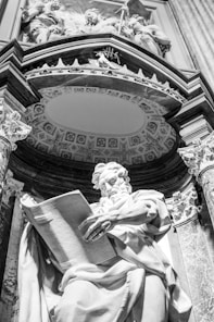 a statue of a man holding a book in front of a building