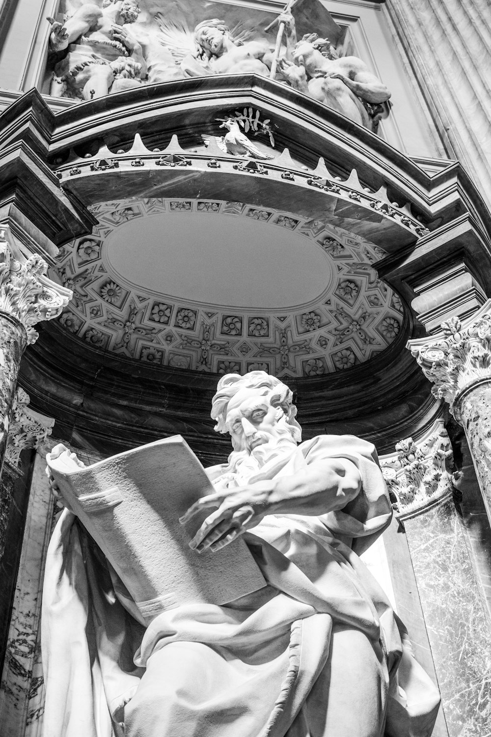 a statue of a man holding a book in front of a building