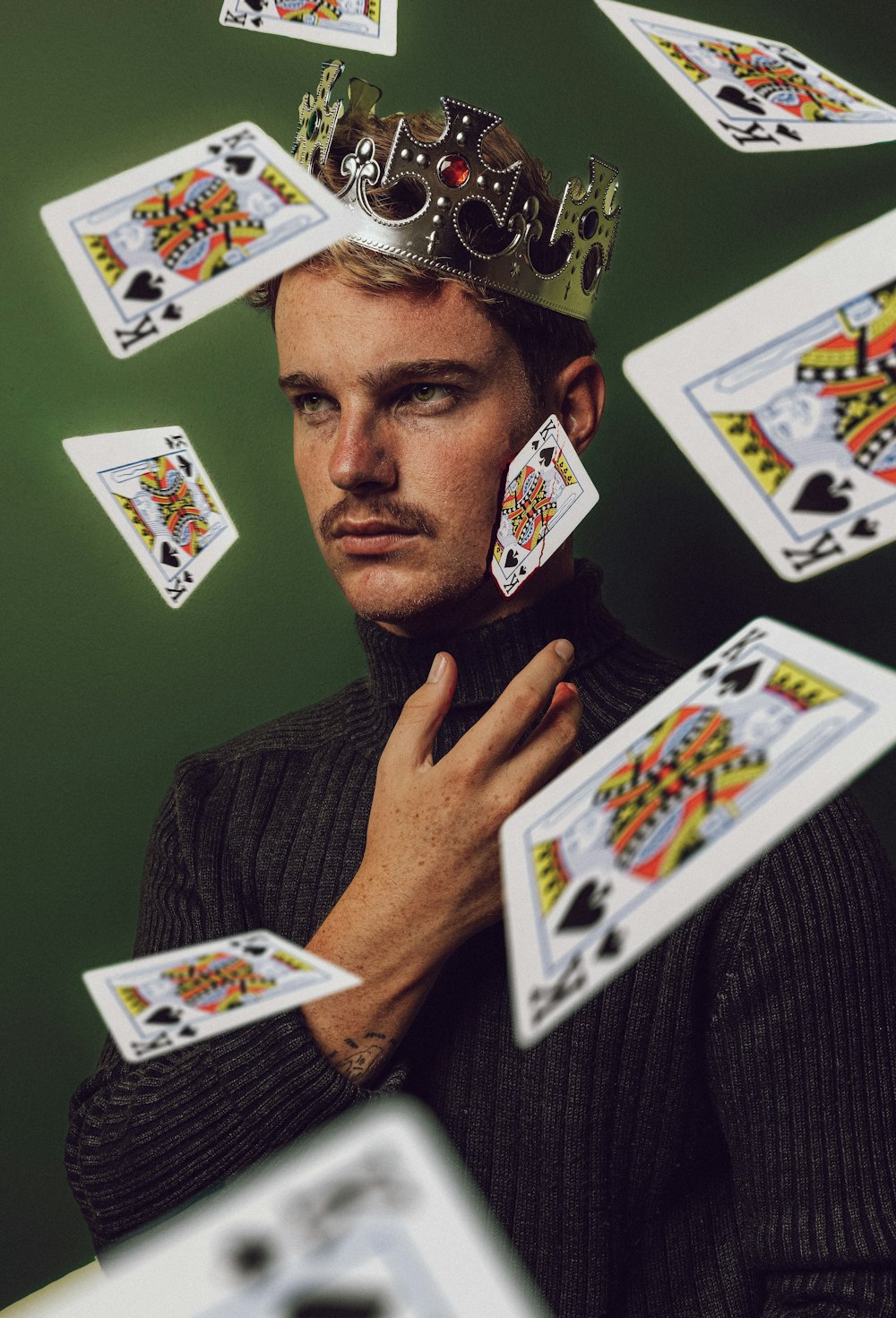 a man with a crown on his head surrounded by playing cards
