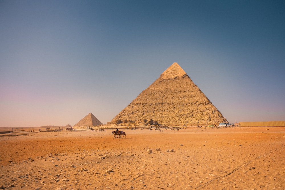 a group of people riding horses in front of a pyramid