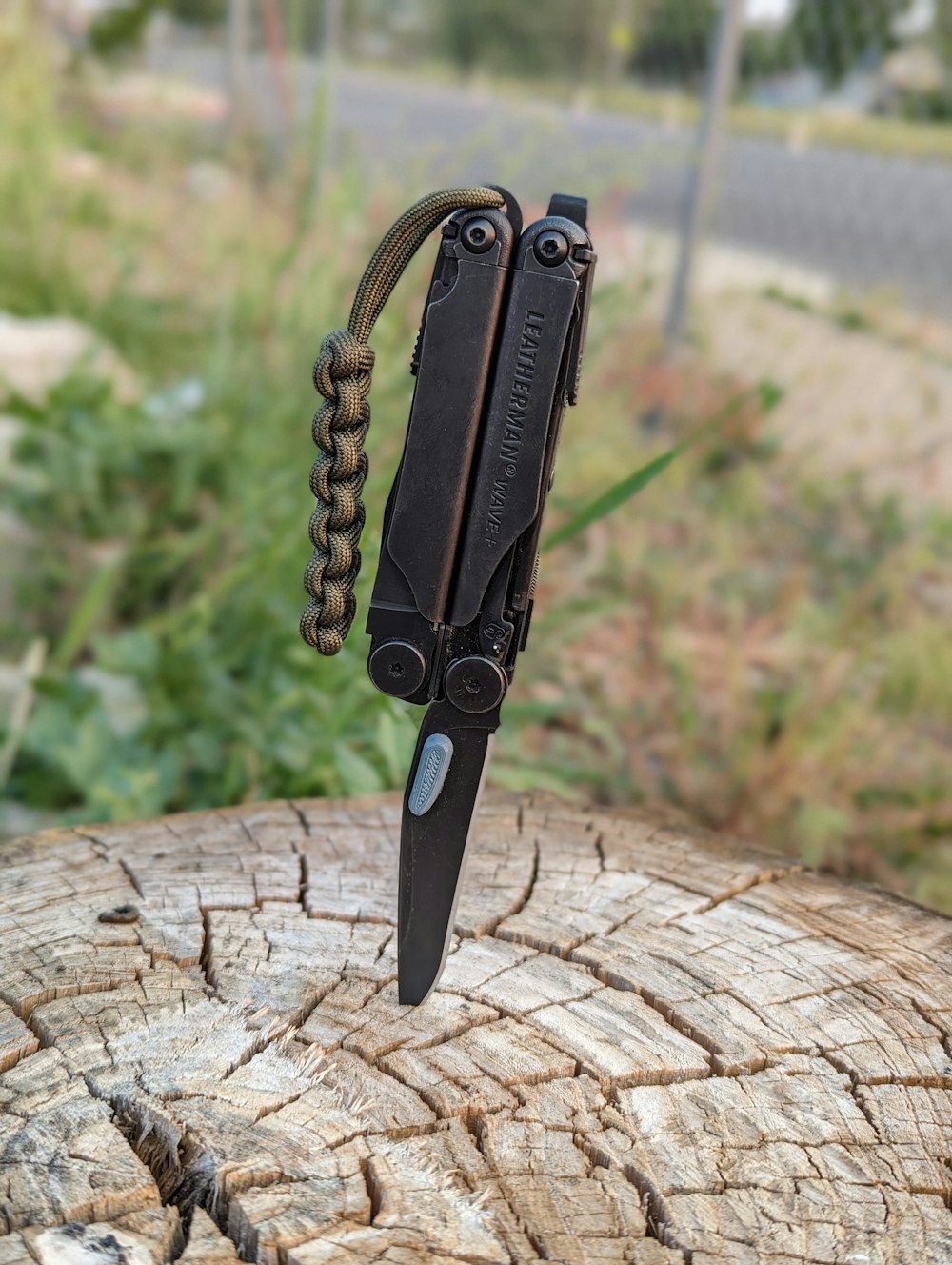 a knife with a chain attached to it sitting on a piece of wood