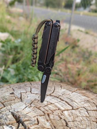 a knife with a chain attached to it sitting on a piece of wood