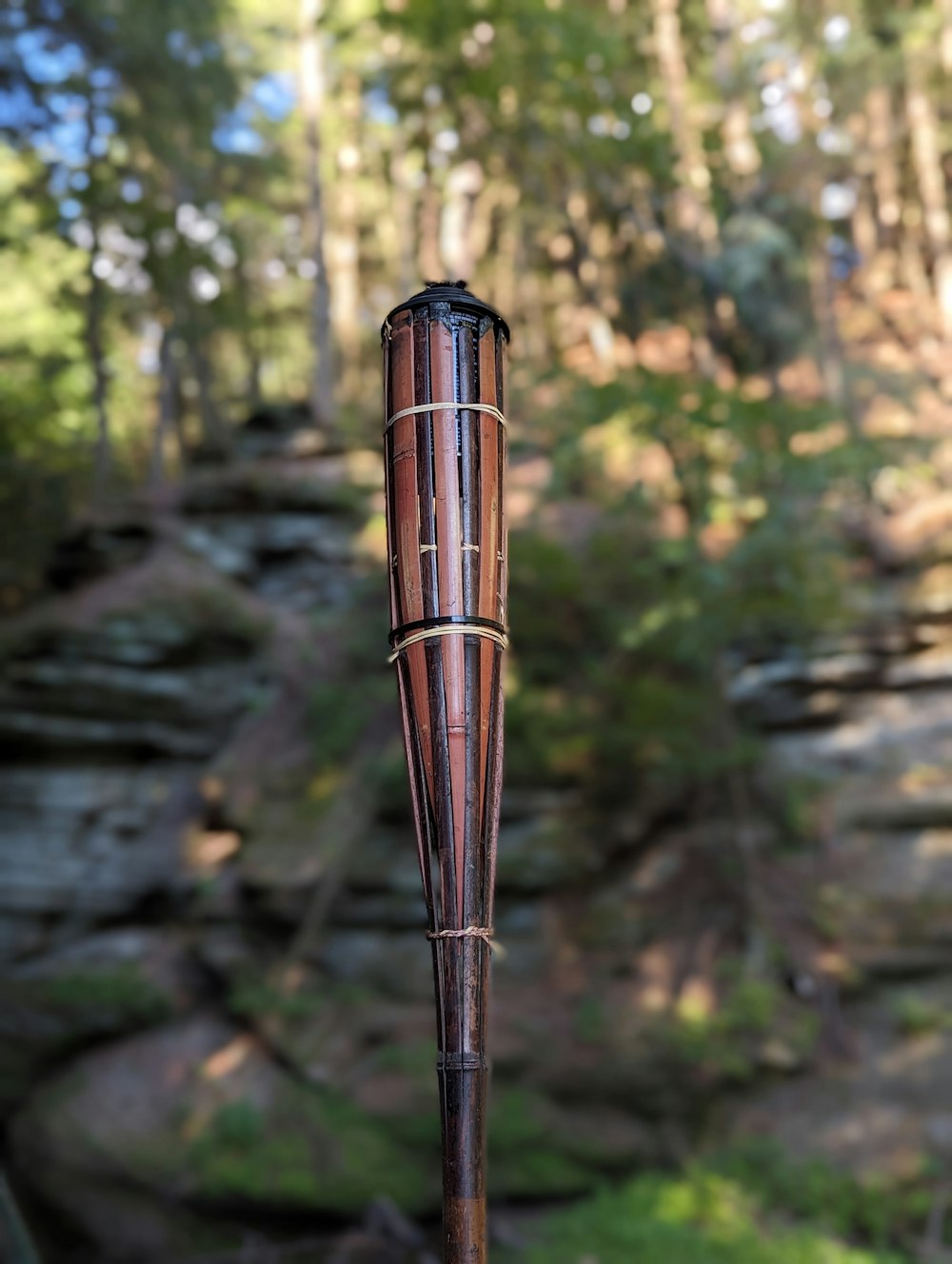 a wooden umbrella stands in the middle of a forest