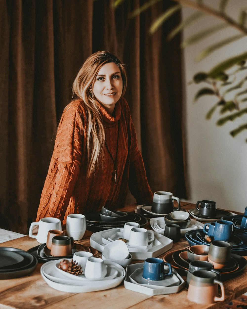 a woman sitting at a table full of cups and saucers
