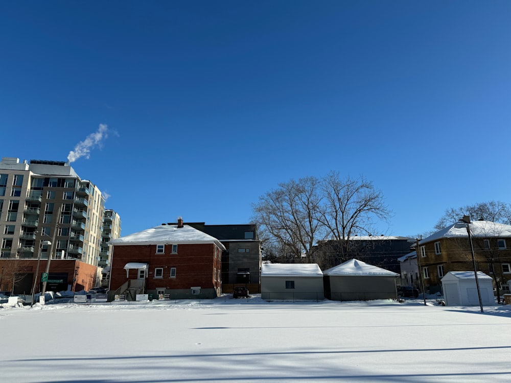 a snow covered field with buildings in the background