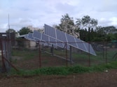 a fence with a bunch of solar panels on top of it