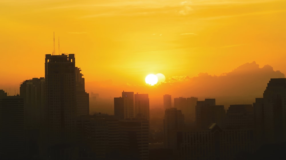 the sun is setting over a city with tall buildings