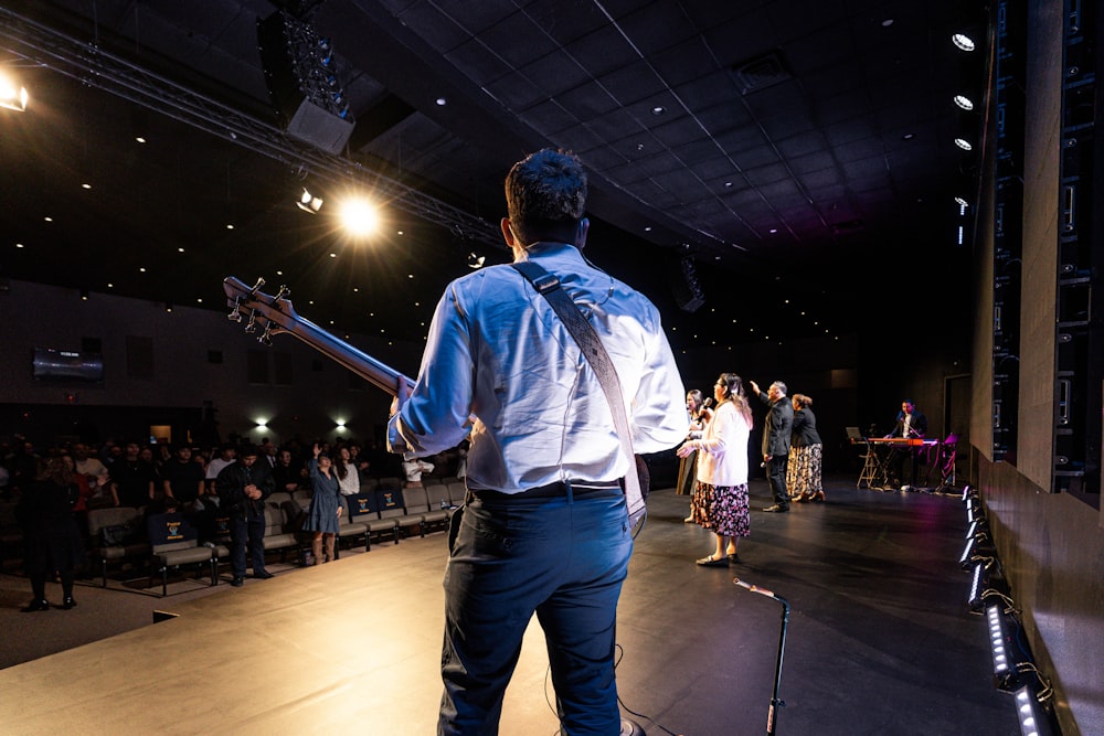 a man standing on a stage holding a guitar