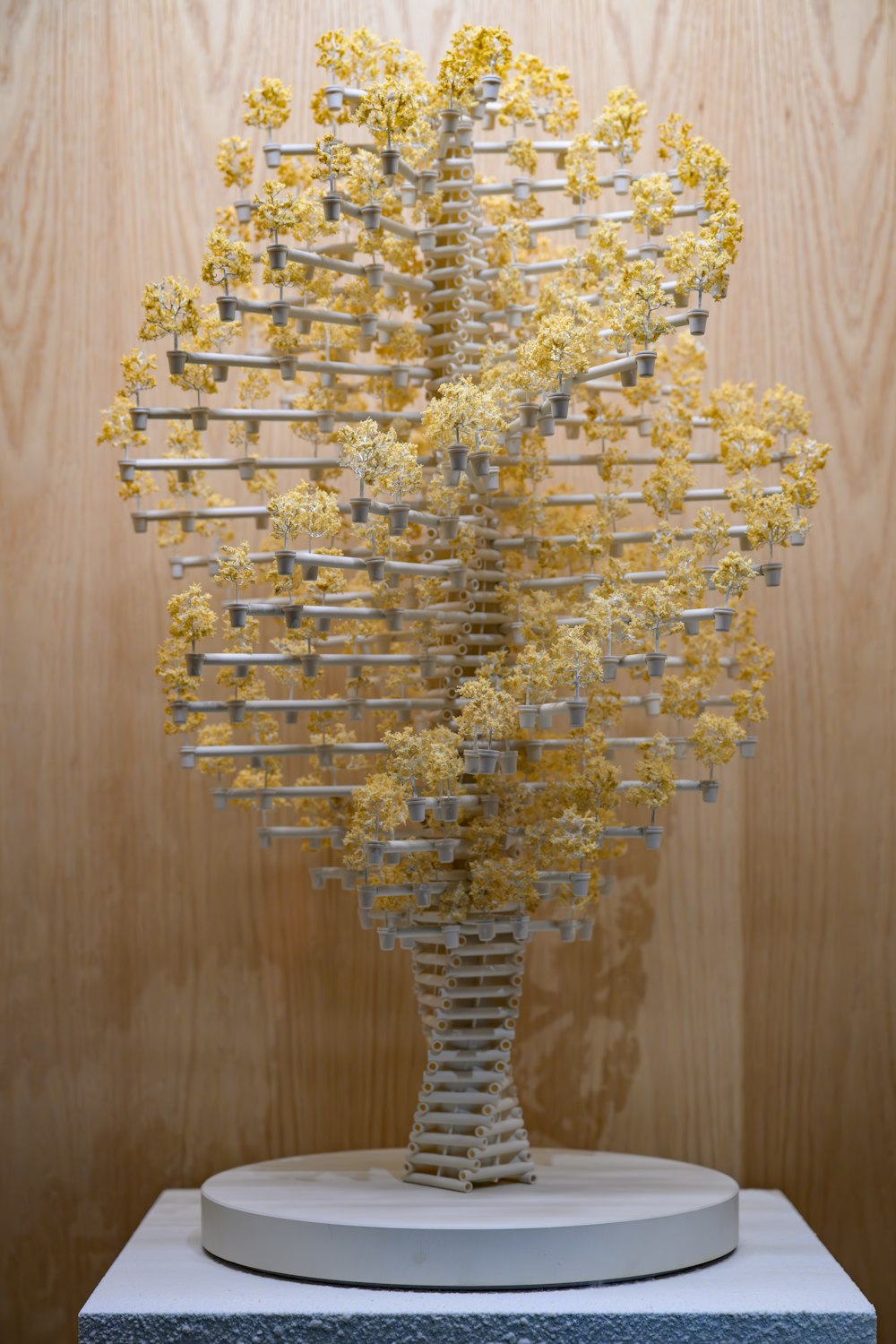 a sculpture of yellow flowers on a white pedestal