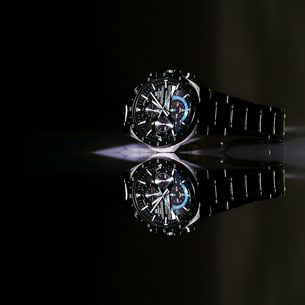 a black watch with a reflection on a black surface