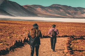 a couple of people walking down a dirt road