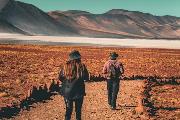 a couple of people walking down a dirt road