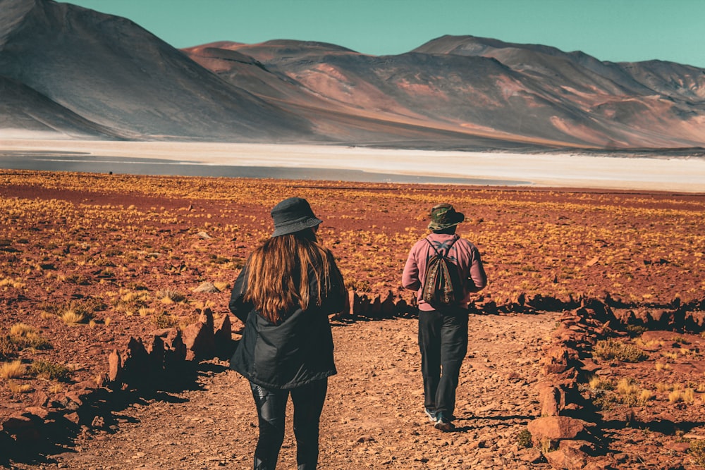 a couple of people walking down a dirt road