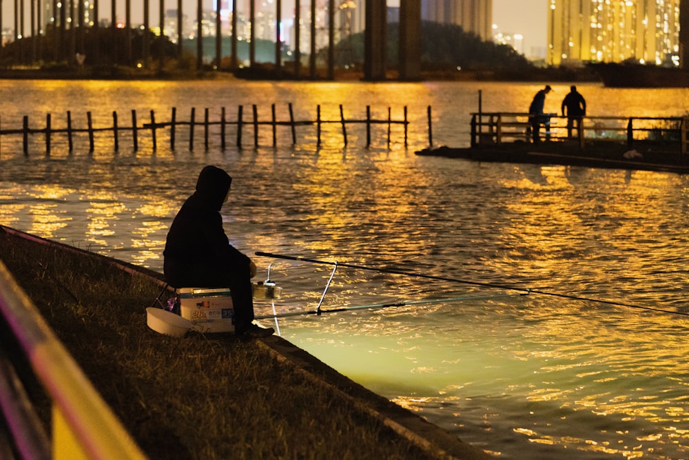 a man sitting on a wall next to a body of water