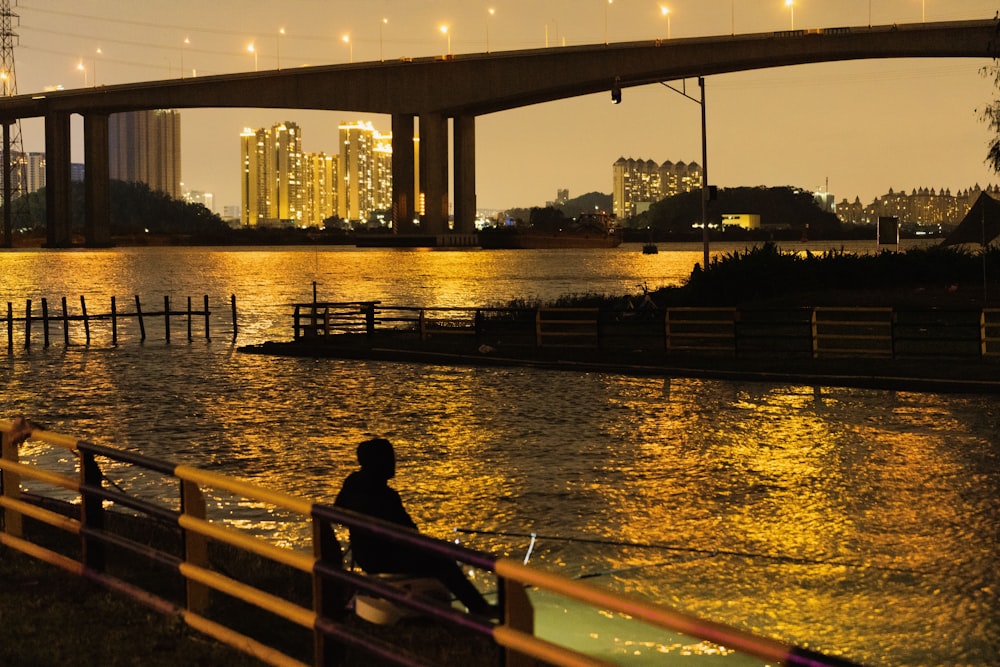 a man sitting on a bench next to a body of water