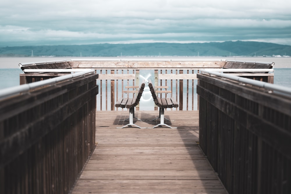 a bench sitting on a wooden pier next to the ocean