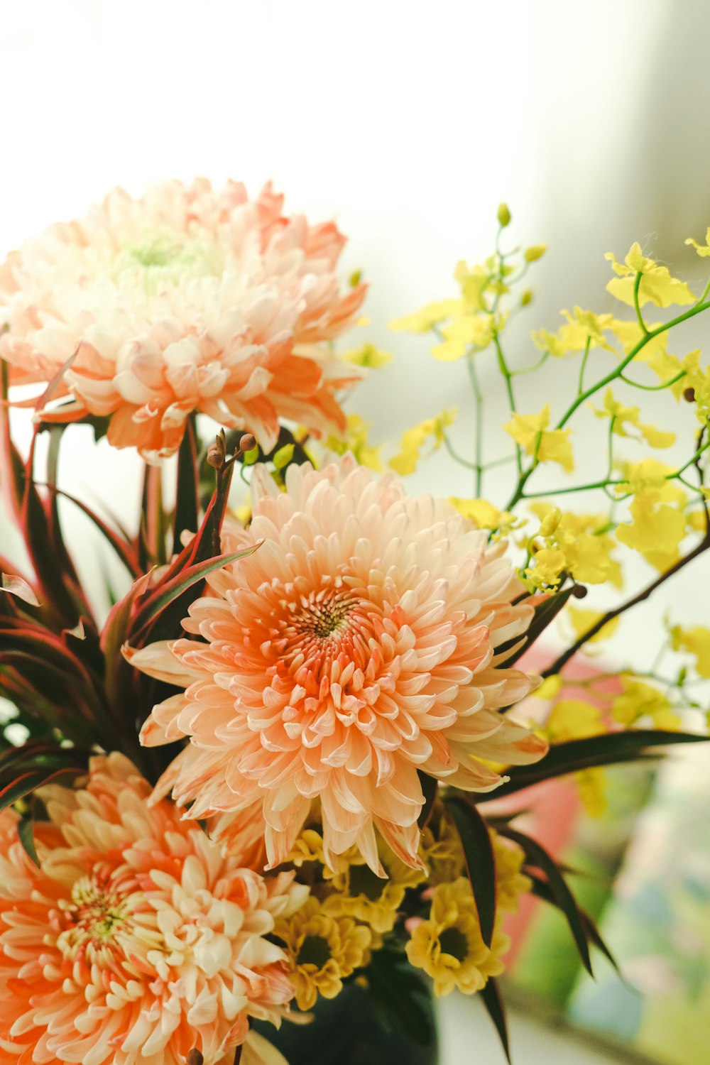 a vase filled with lots of pink and yellow flowers