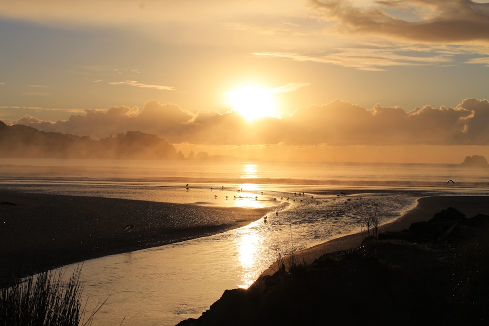 the sun is setting over the water at the beach