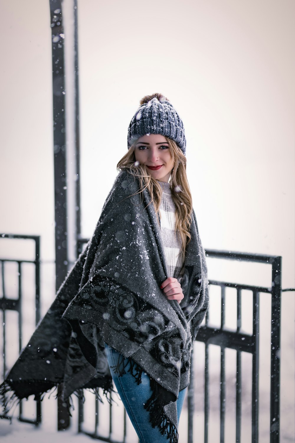 a woman standing in the snow with a blanket over her