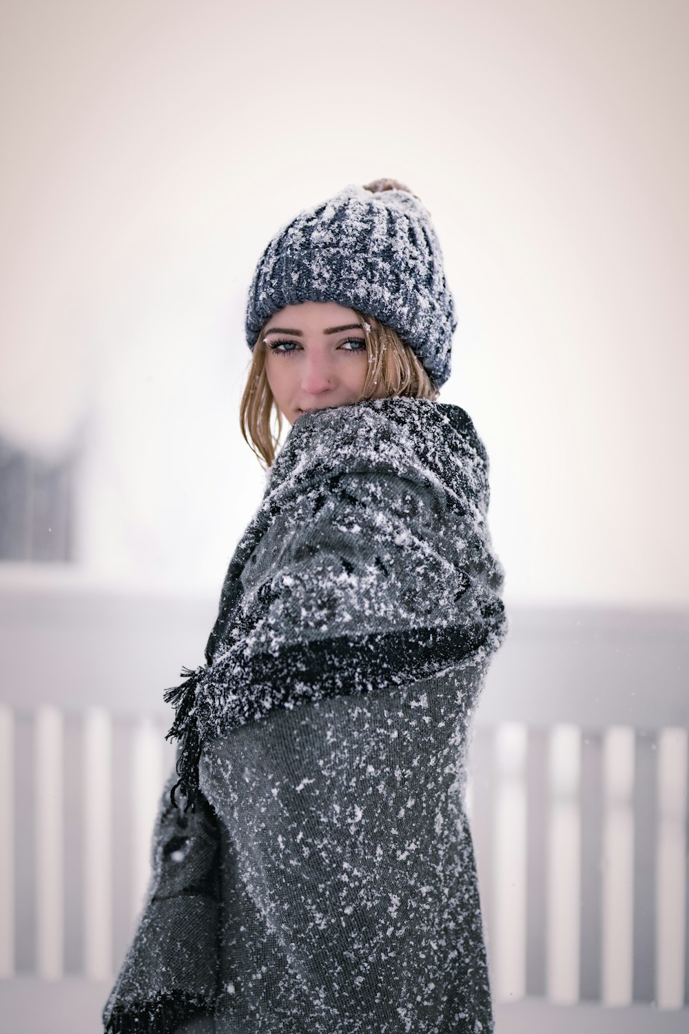 a woman in a coat and hat standing in the snow