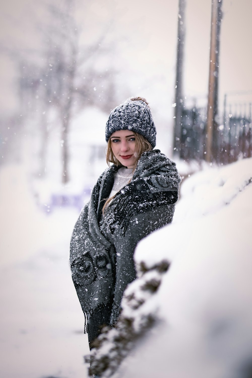 a woman standing in the snow wearing a coat