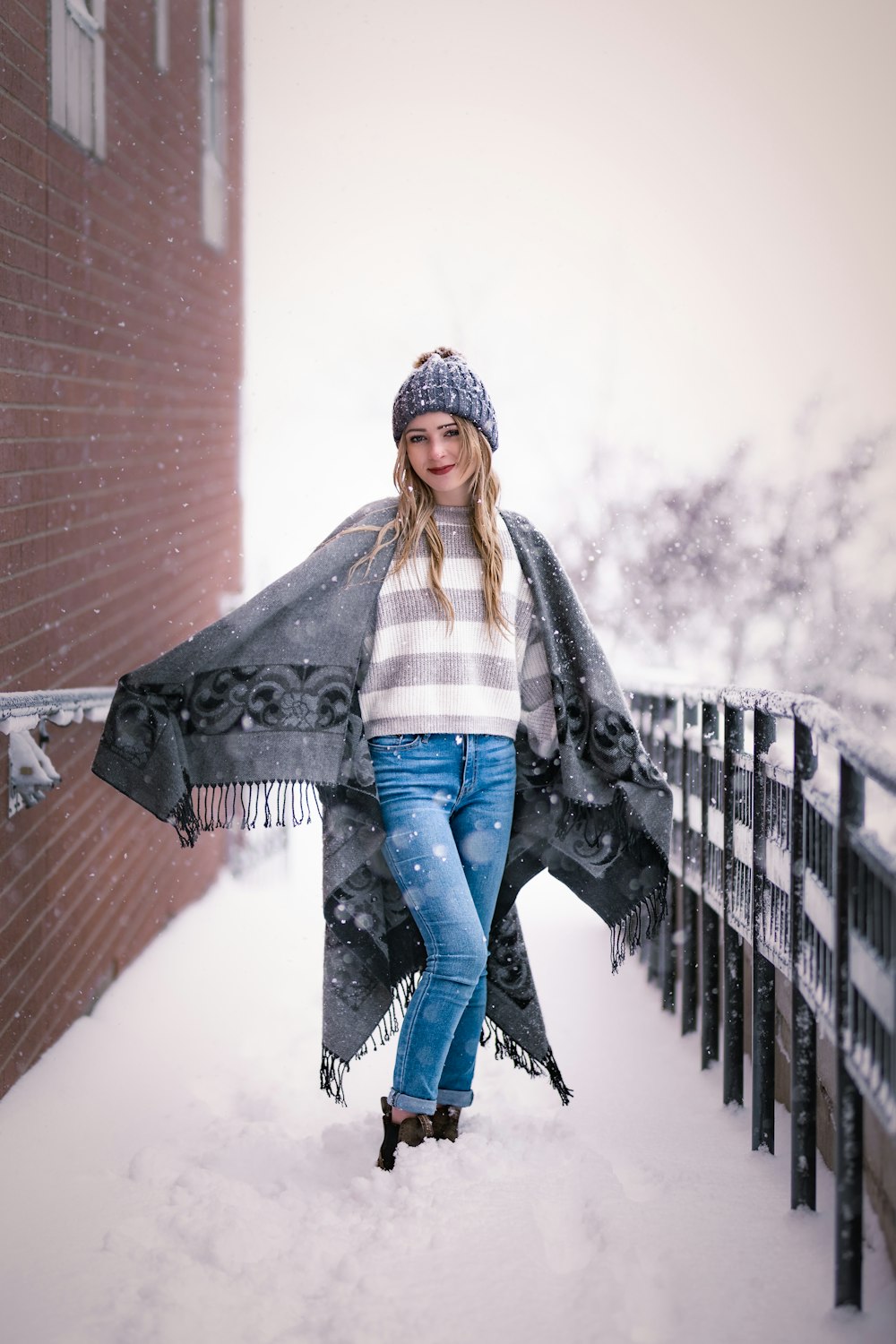 a woman is standing in the snow with a blanket