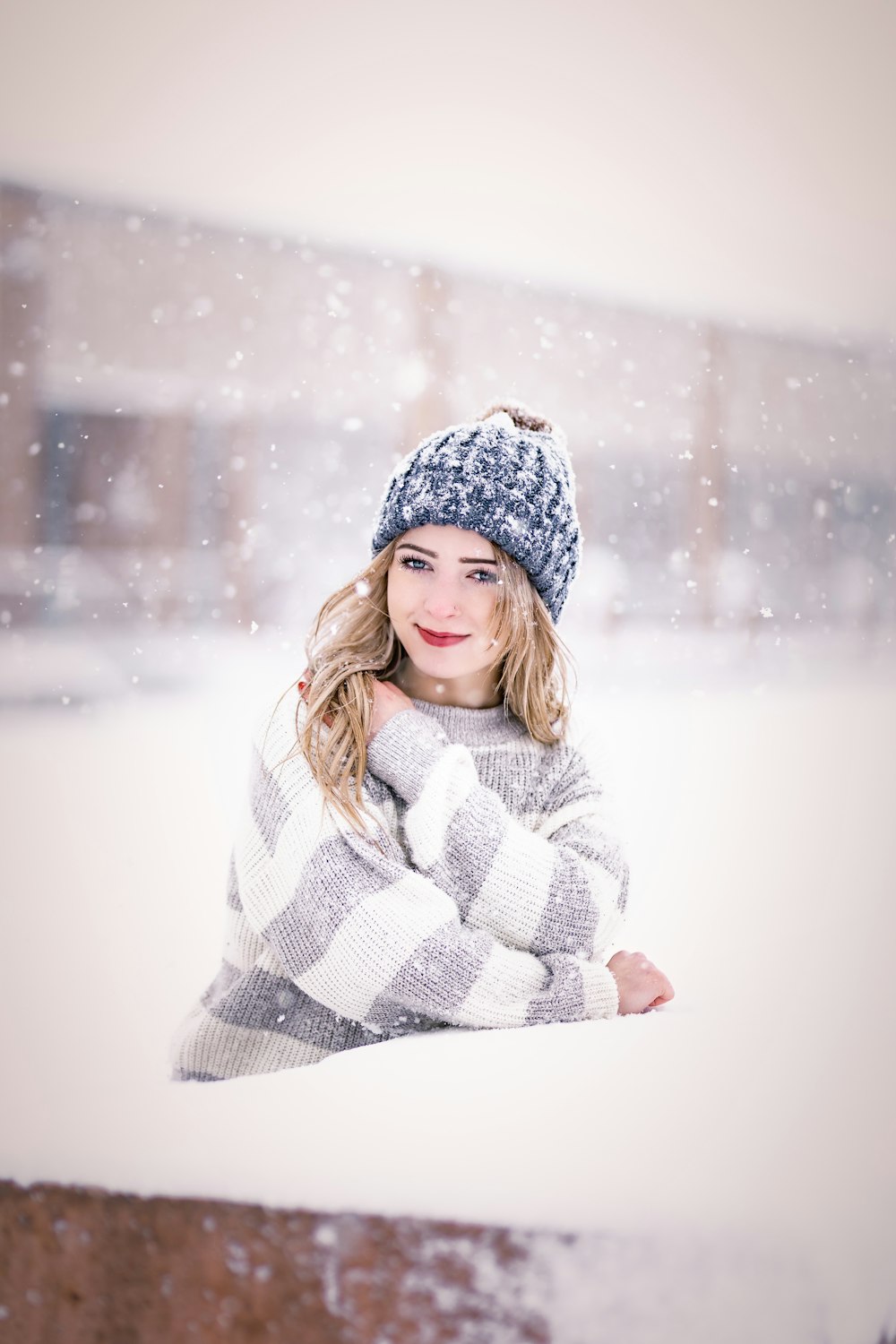 a woman wearing a hat and sweater standing in the snow