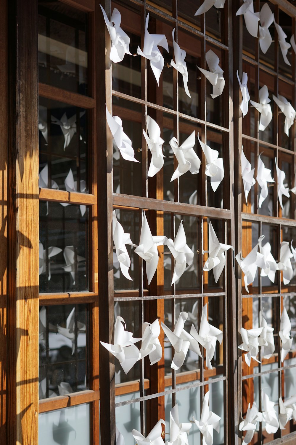 a bunch of white paper birds hanging from a window