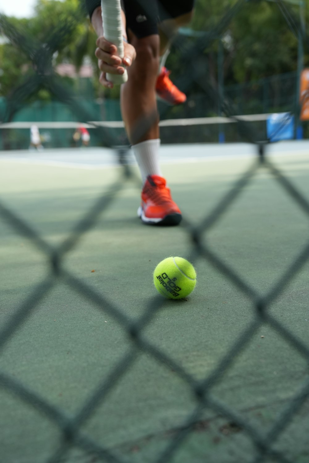 a tennis ball on a court with a person standing behind it