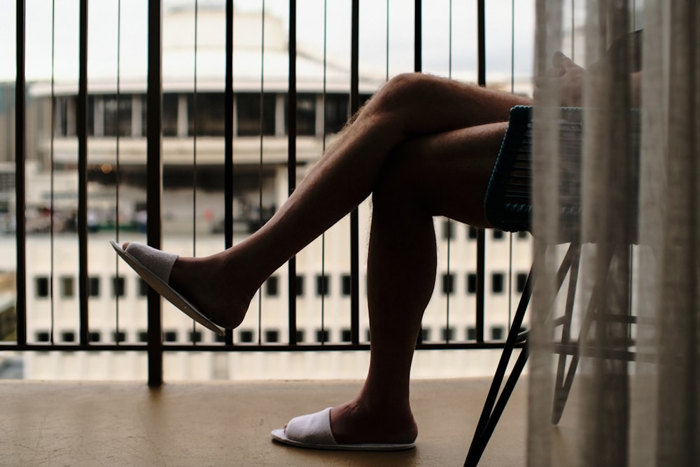 uma pessoa sentada em uma cadeira com as pernas cruzadas