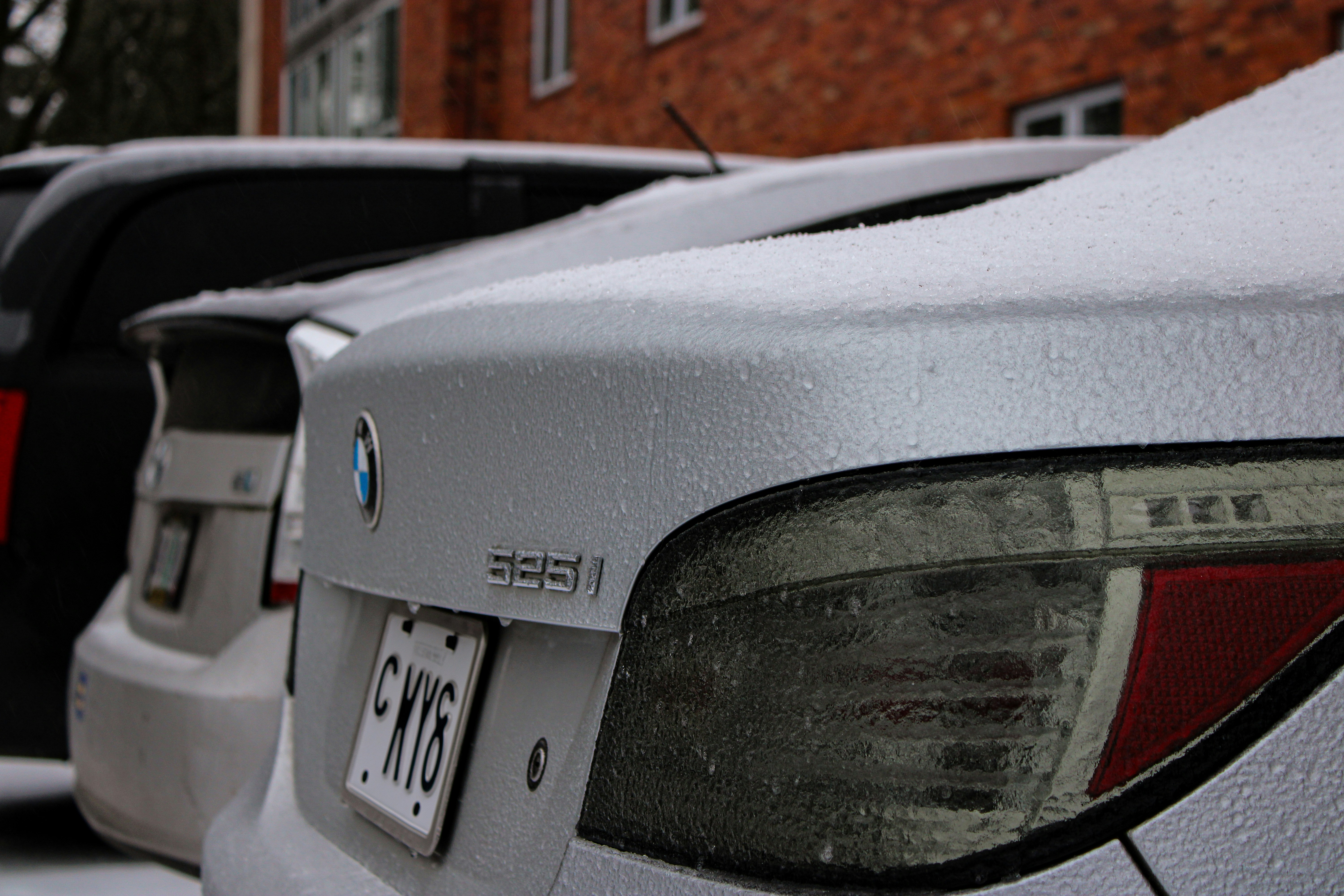 eine Reihe geparkter Autos, die mit Schnee bedeckt sind