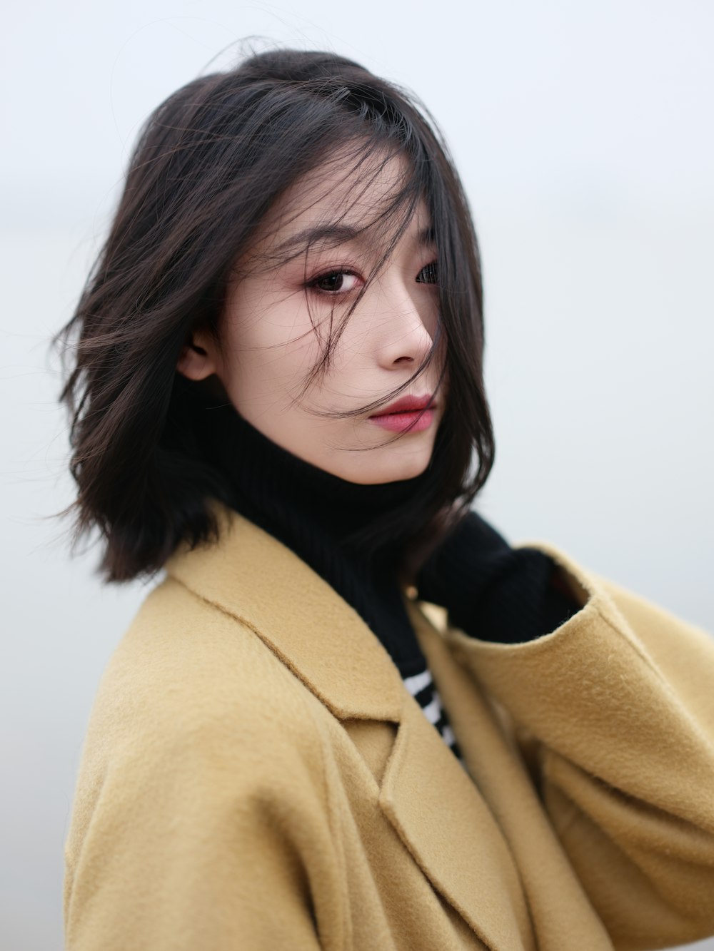 a woman in a yellow coat posing for a picture