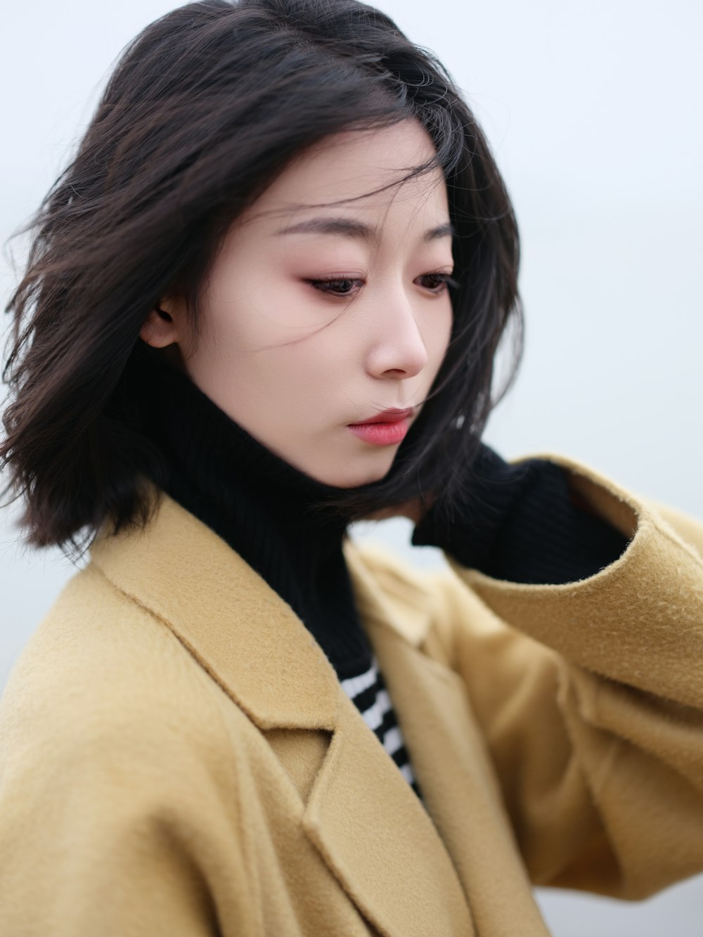 a woman in a yellow coat is looking at her cell phone