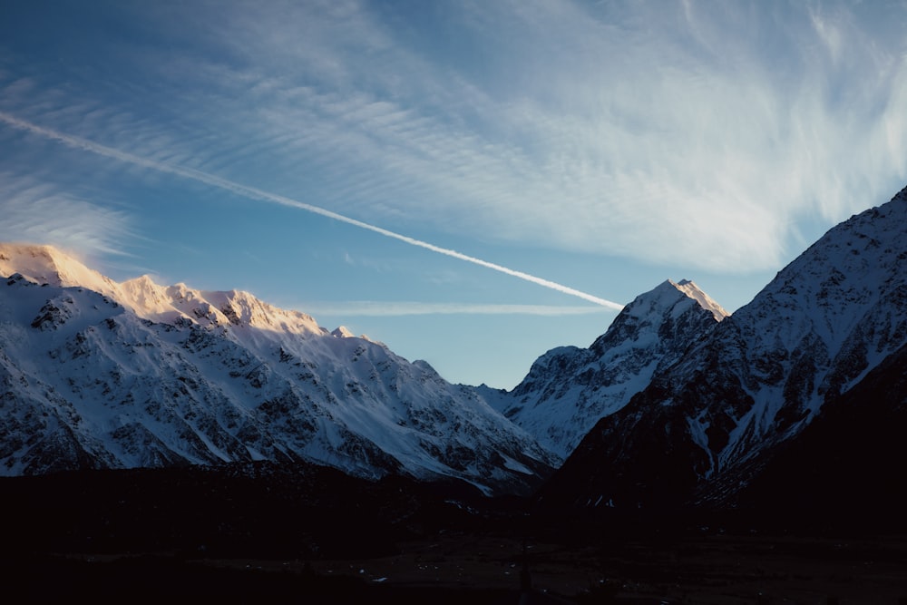 the mountains are covered in snow as the sun sets