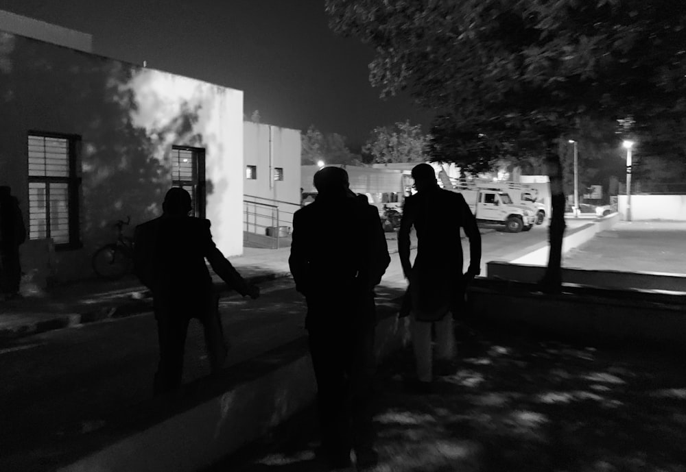 a group of people walking down a street at night