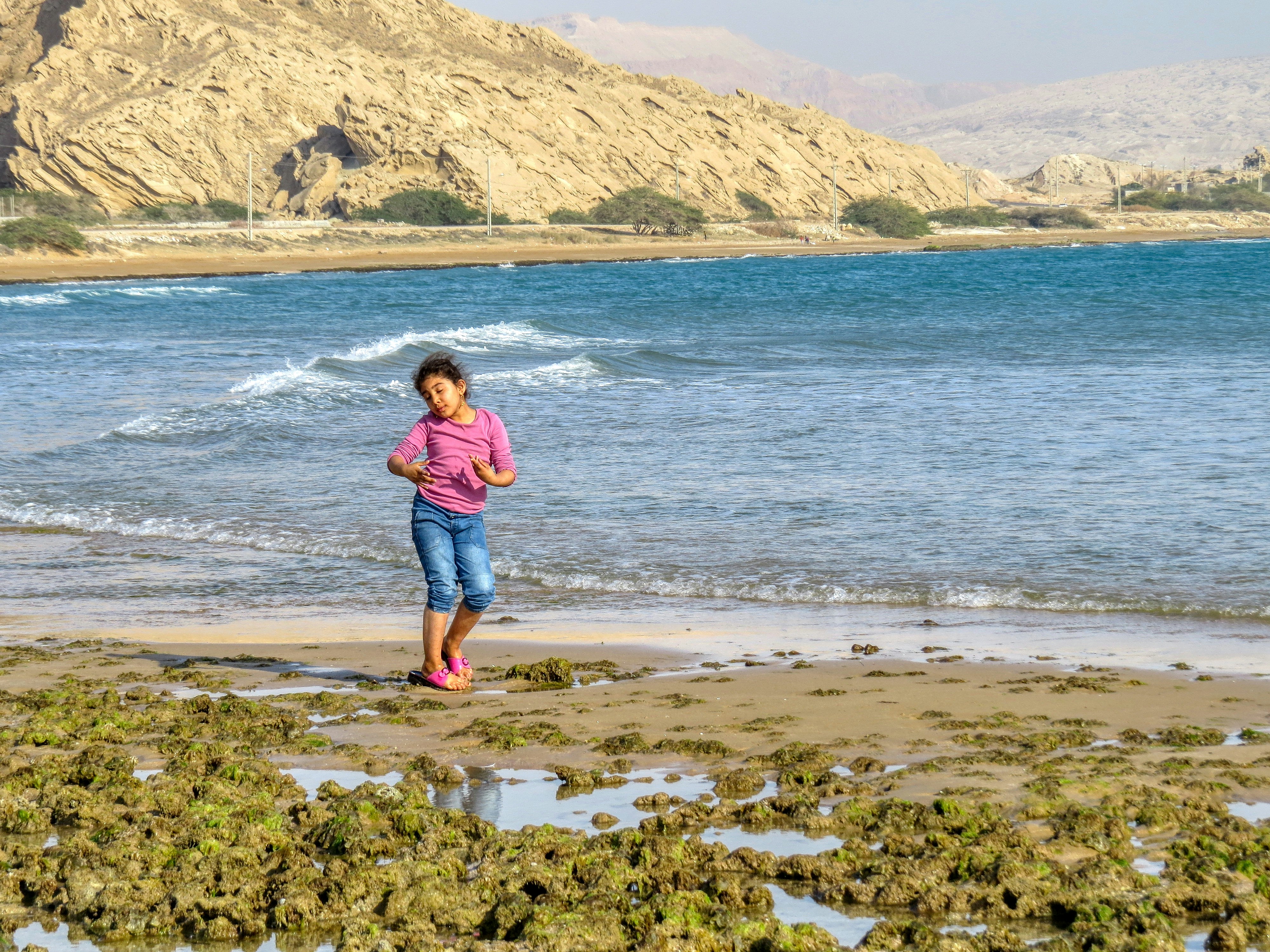 a woman standing on top of a sandy beach next to the ocean