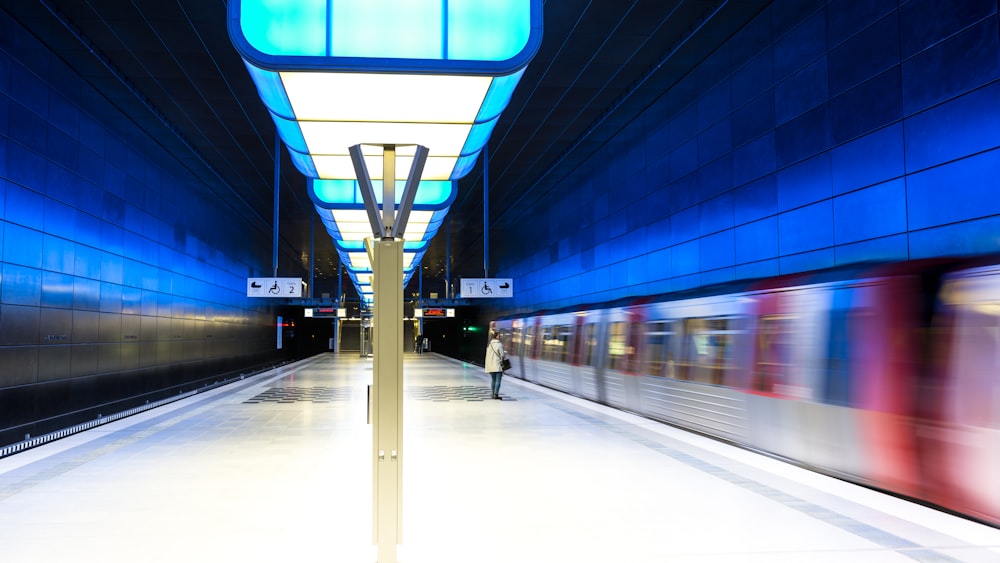 a subway station with a person walking on the platform