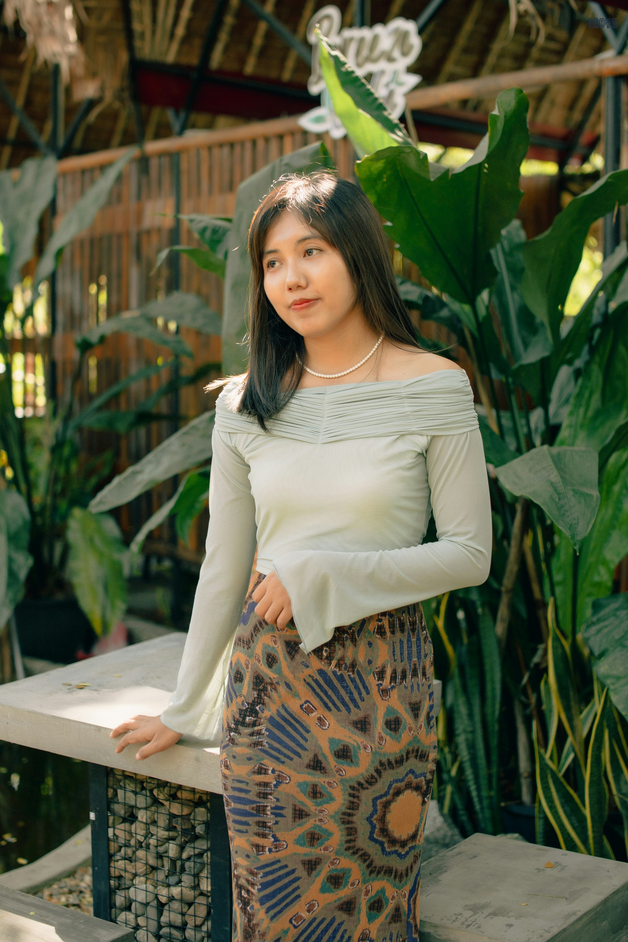 eine Frau steht auf einer Bank vor einigen Pflanzen