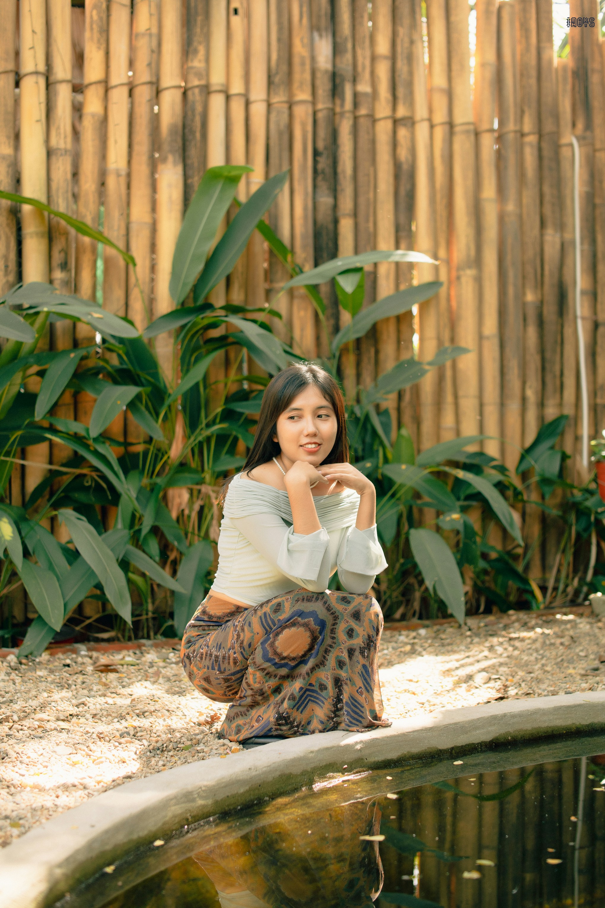eine Frau sitzt auf dem Boden neben einem Teich