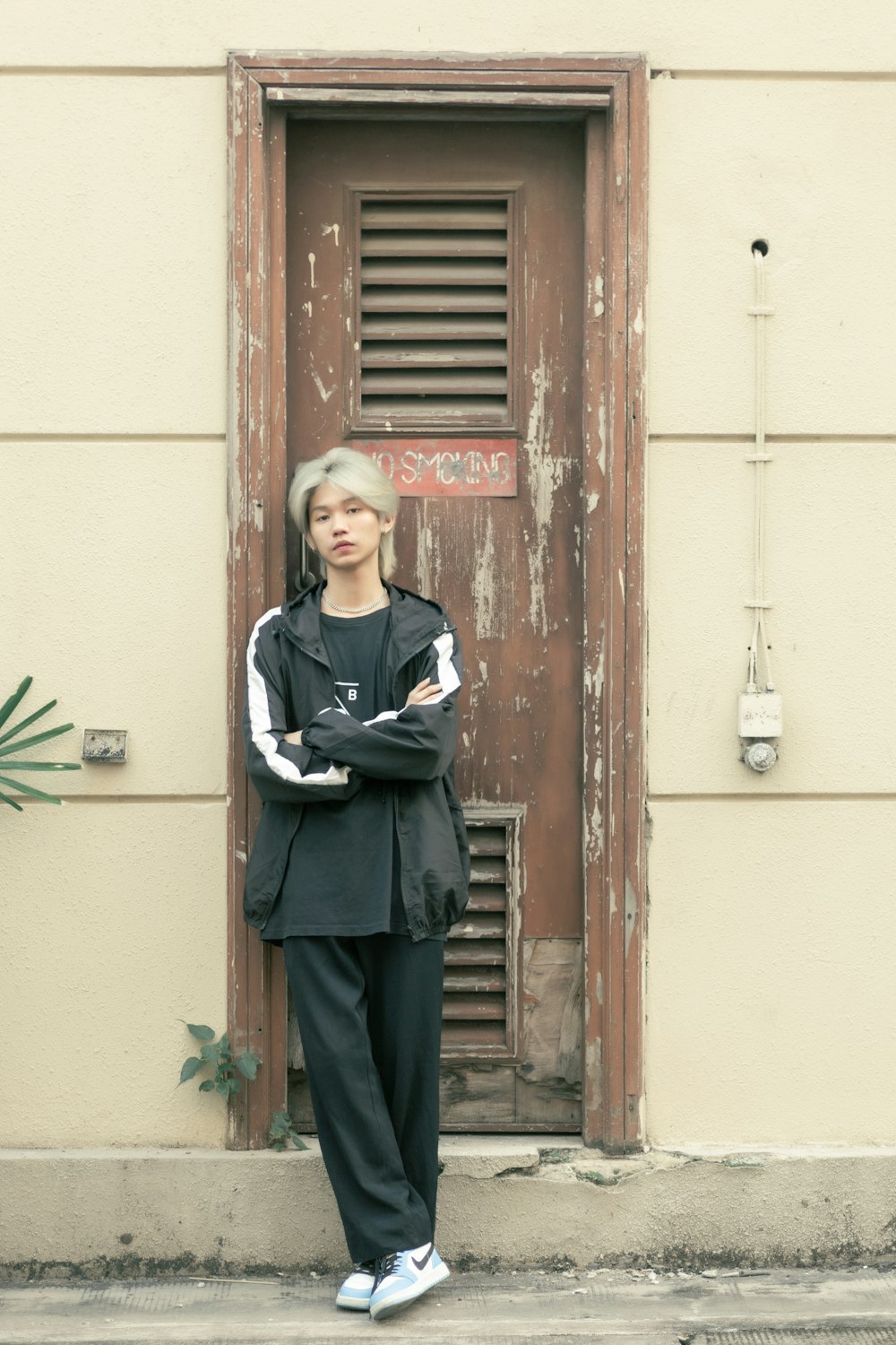 a woman standing in front of a door with her arms crossed