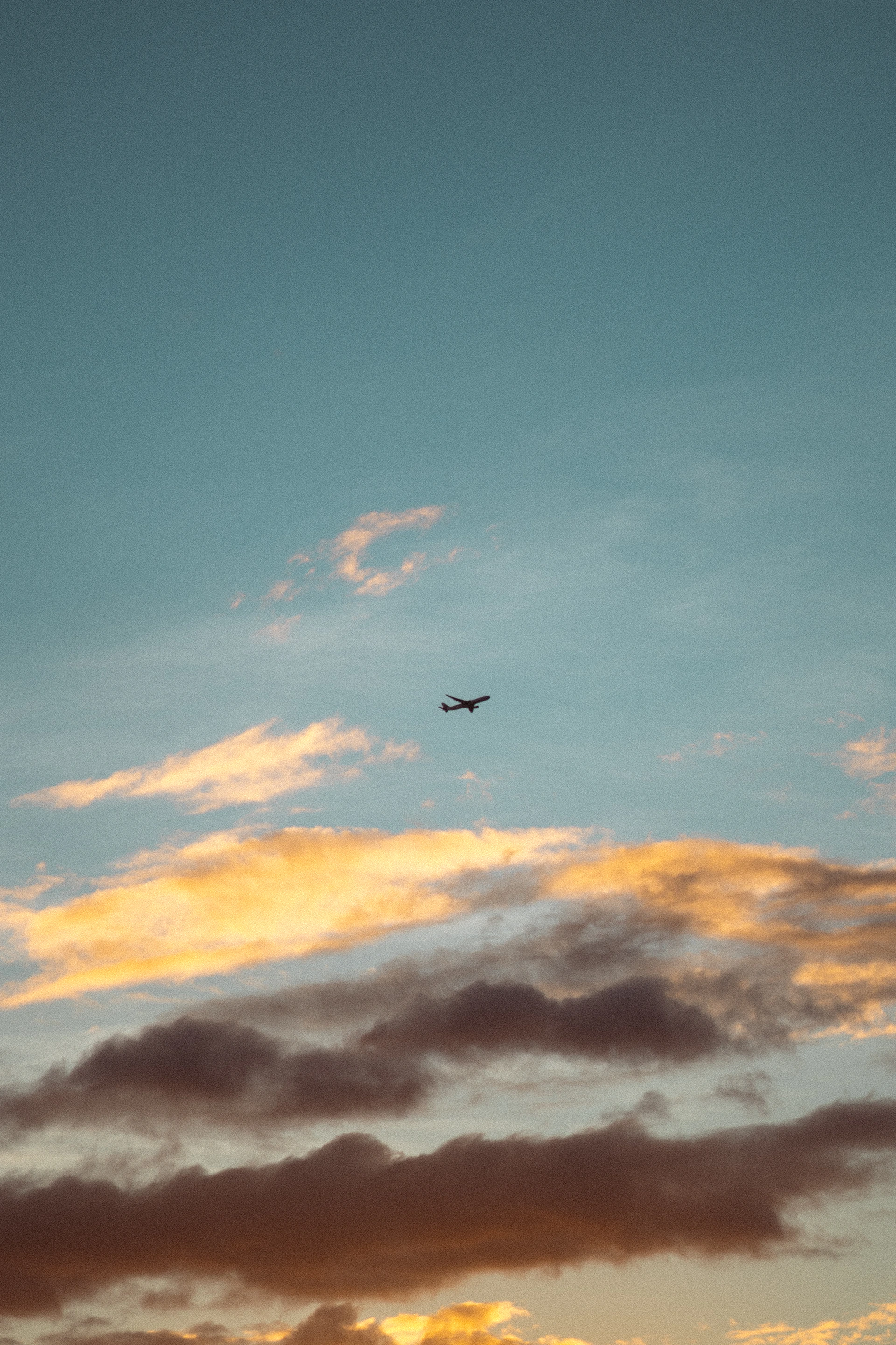 a plane flying in the sky at sunset