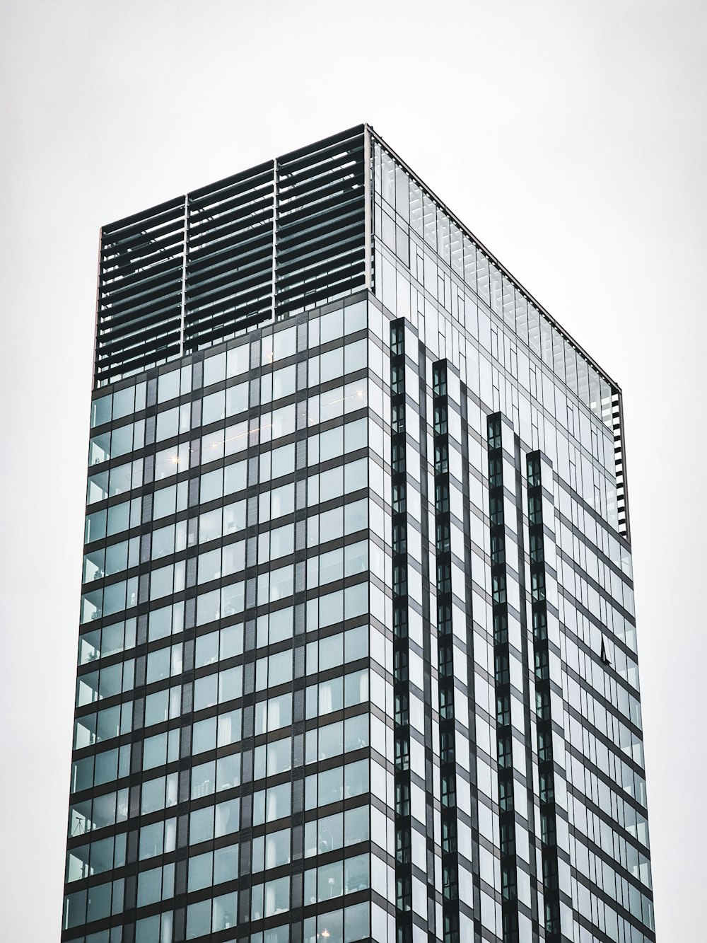 a very tall glass building with a clock on it's side