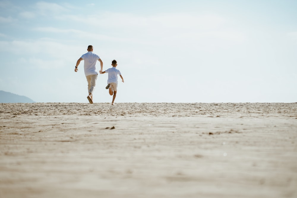 a man and a woman running across a sandy beach
