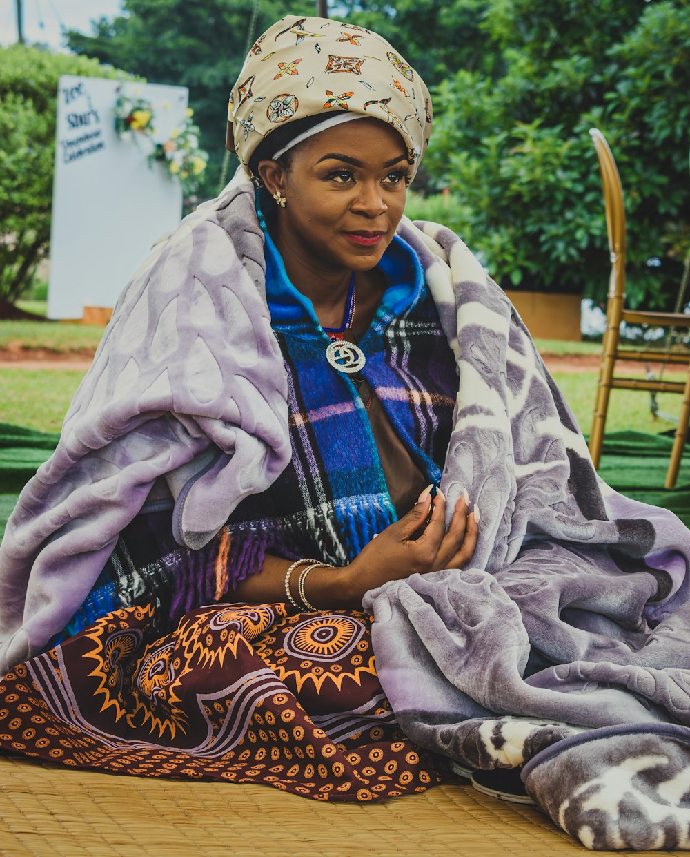 a woman sitting on the ground under a blanket