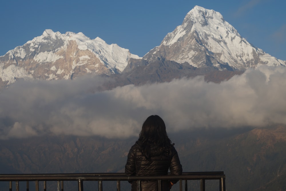 una mujer de pie en un balcón mirando una cadena montañosa